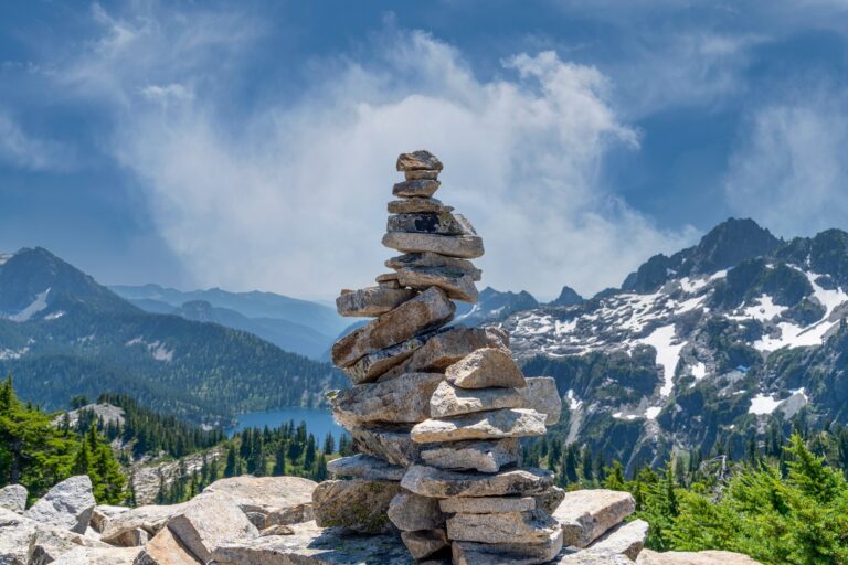 A pile of stones in a mountain scenario with a lake in the backdrop.