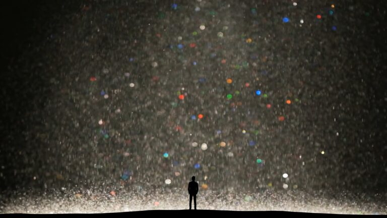 La foto rappresenta una sfondo celeste illuminato da una corrente bianca e diversi punti colorati con la figura umana in sovra impressione.