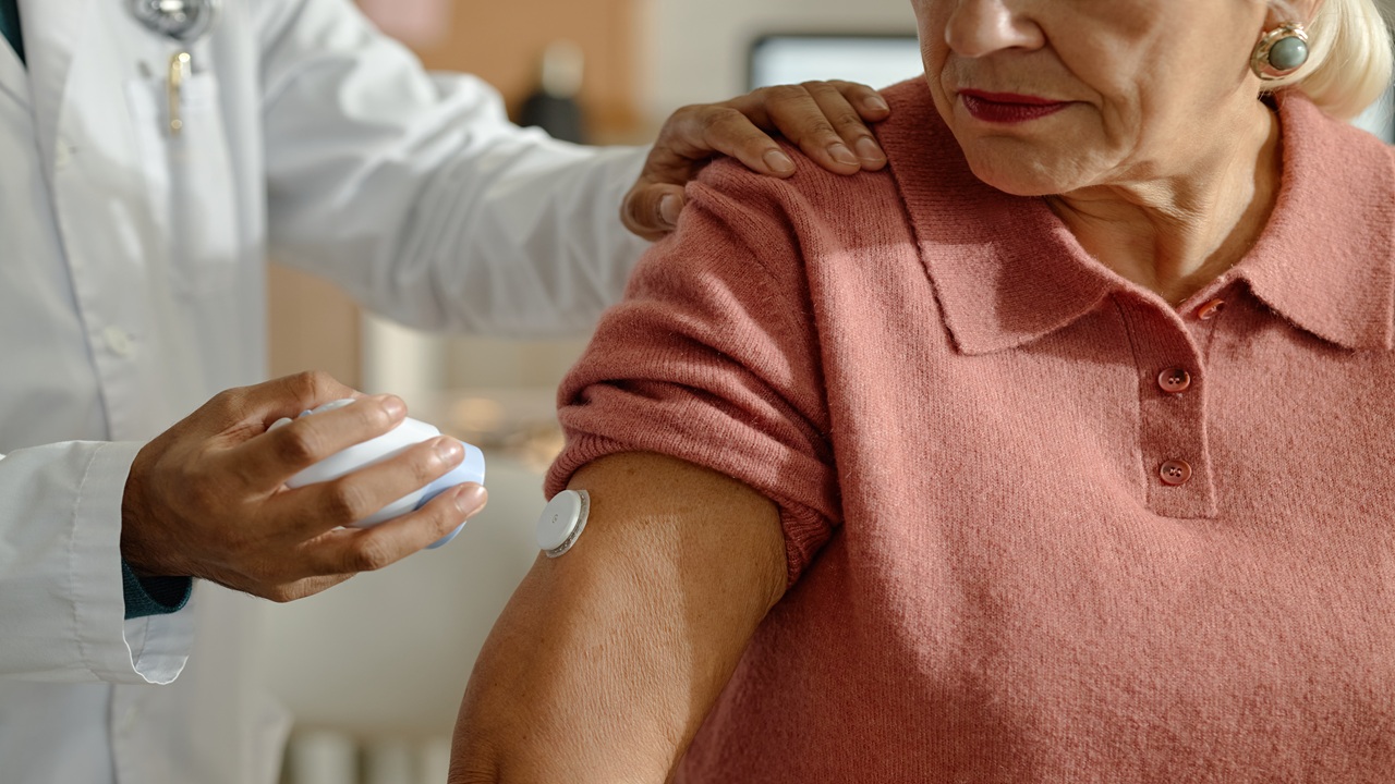 Senior woman receiving medical sensor placement from doctor in clinic, supporting chronic care monitoring and preventive healthcare. Close up, ideal for telehealth or patient care marketing